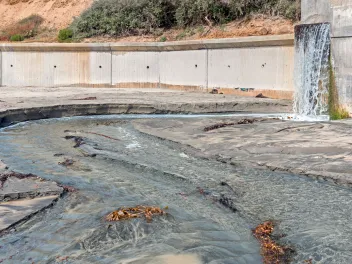 Hillside storm drain runoff on sandy beach