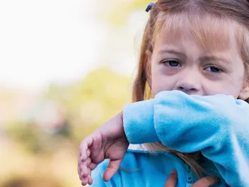 Girl coughing into her elbow