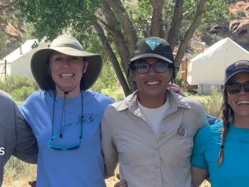 Photo of Bureau of Land Management and nonprofit partners arm in arm smiling.