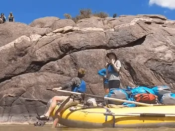 Student on raft next to big canyon rock during experiential education trip