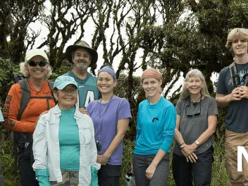 group of women and men part of the Army Natural Resource Program standing together smiling outside in front of trees and bushes.