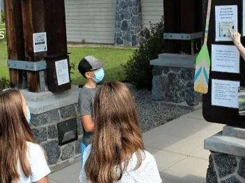 Forest Service staff pointing to announcement board instructing group of middle school students. 